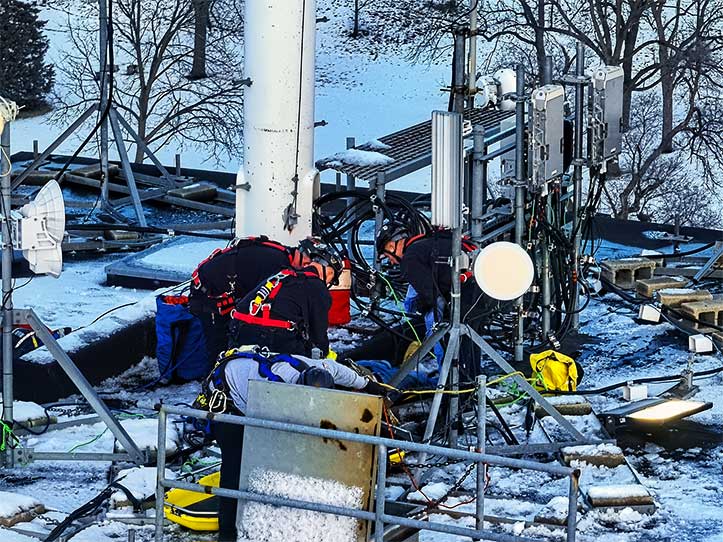 HIGH RESCUE workers prepare to load the injured worker at the base of a monopole onto a basket stretcher that was lowered through the entrance hatch and then out of a grainery tower to waiting firefighters.